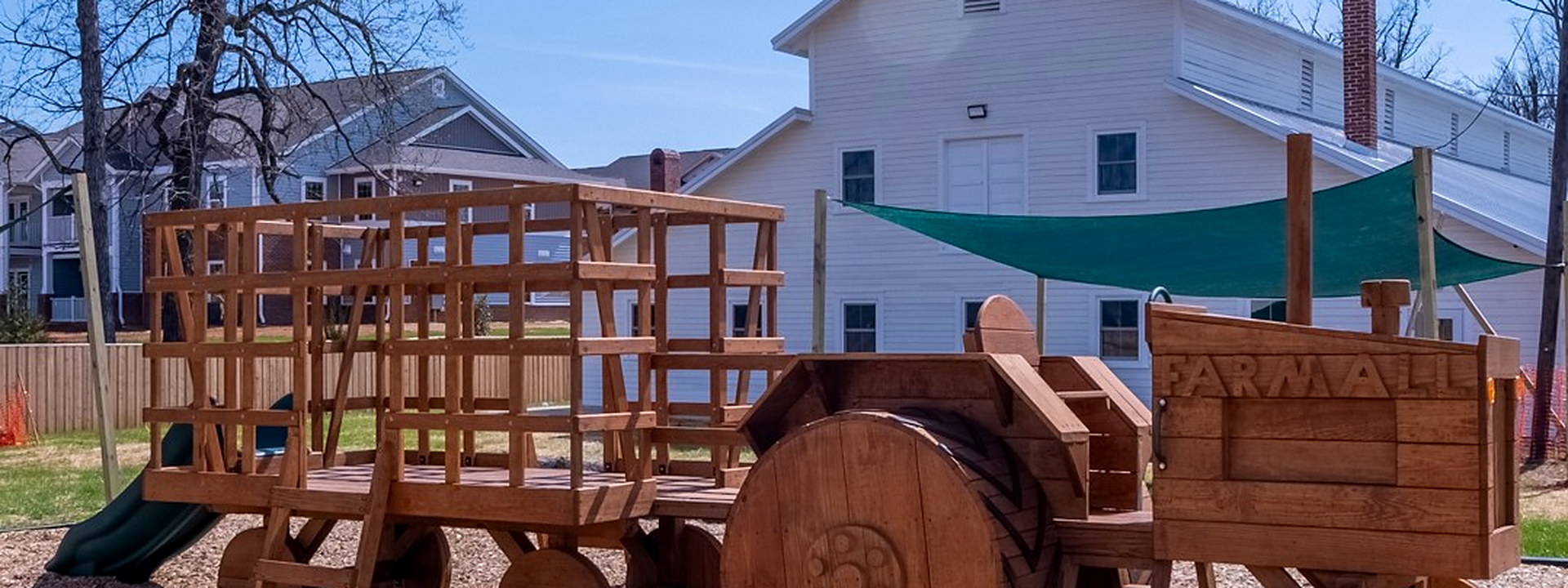 Wooden farm-truck play structure on the outdoor playground at The Giving Tree Montessori School.