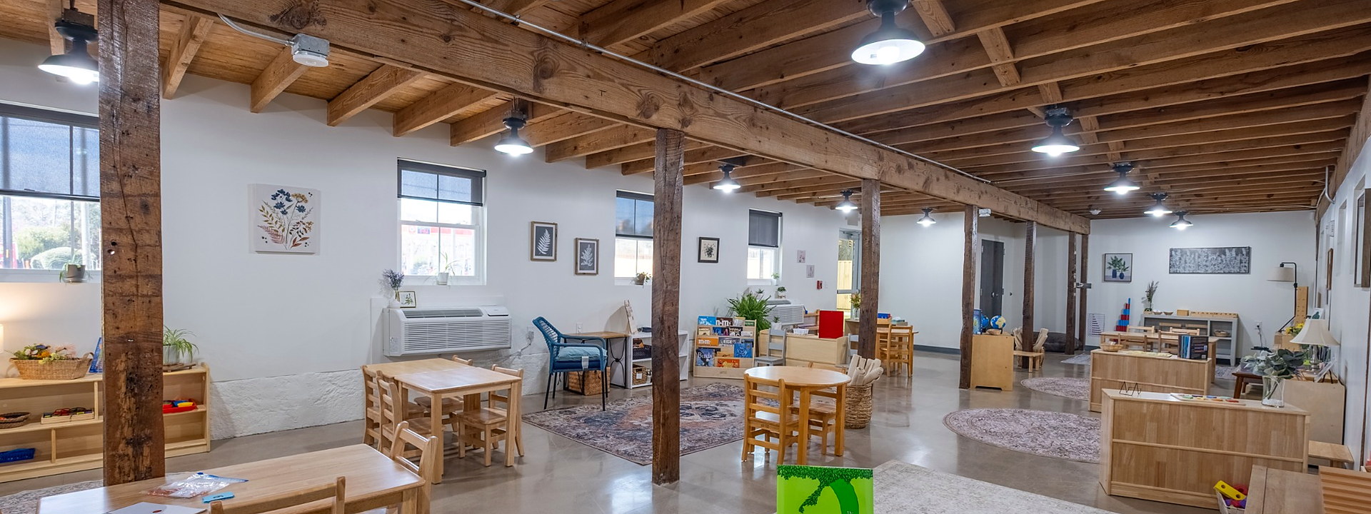 Prepared Montessori classroom with child-sized tables, shelves, and learning materials.
