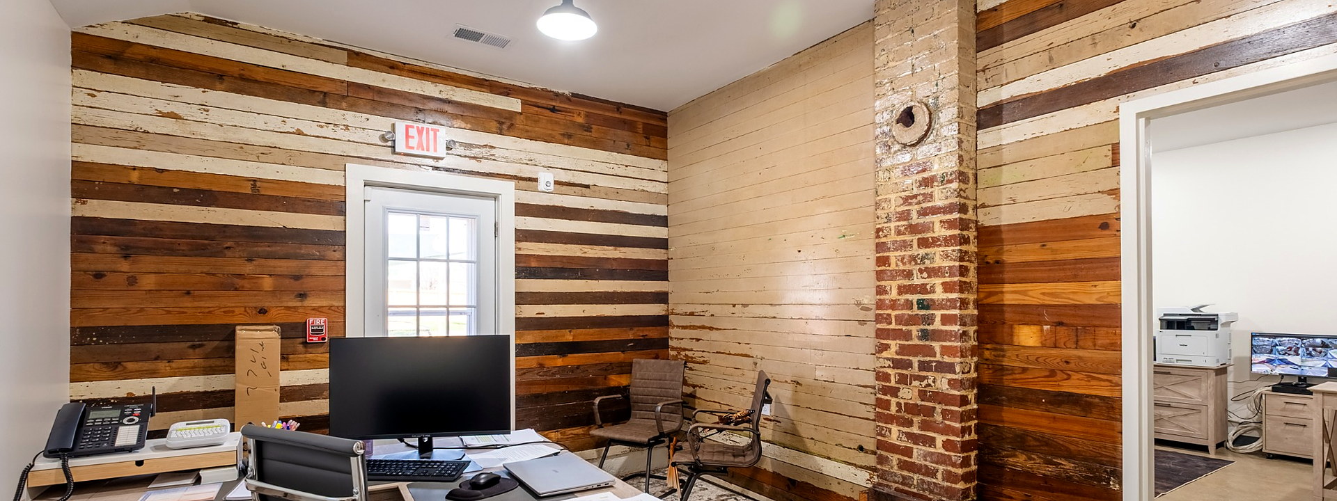 School administrative office featuring restored wood walls and a historic brick column.