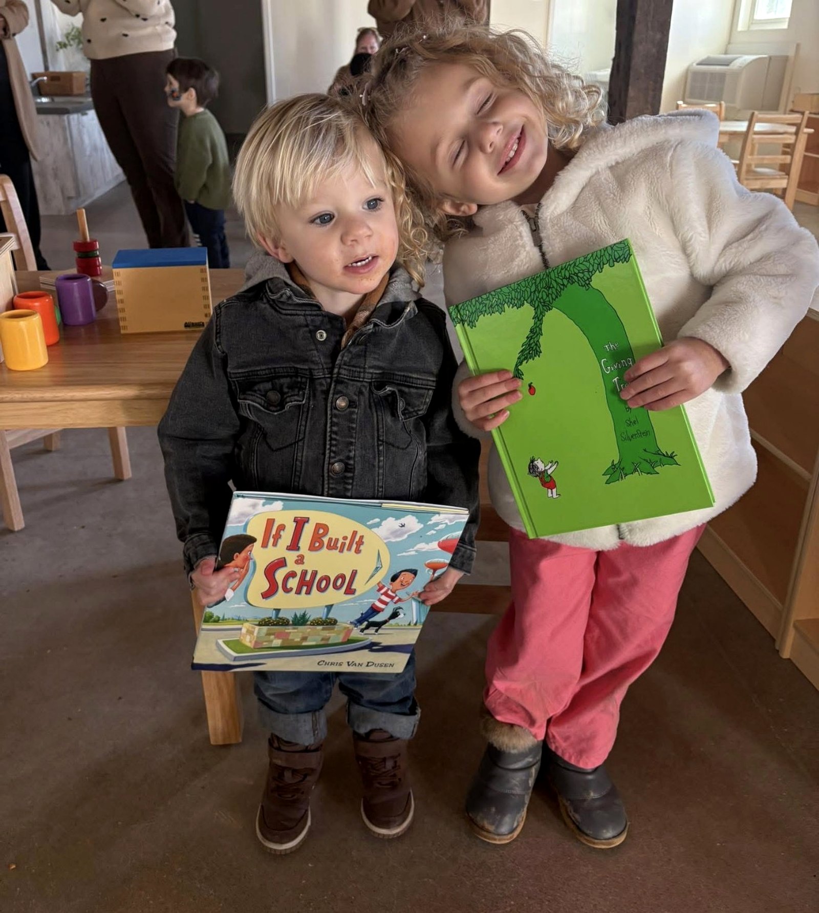 Athena and Theo holding books together in a Montessori classroom.