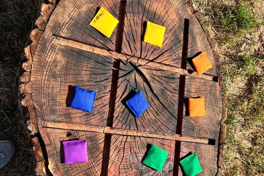 A large tree round marked out as a noughts-and-crosses grid, with coloured bean bags placed in the squares.