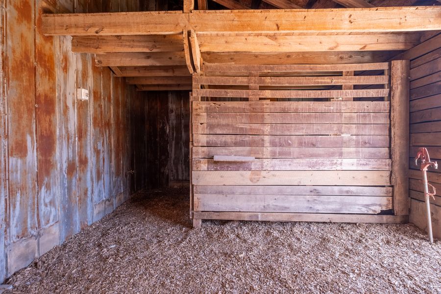 A stall door marked with a painted number set into weathered board walls beneath heavy timber framing.