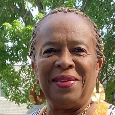 Georgia Marshall, Office Administrator — smiling woman with braided hair and large gold earrings outdoors.