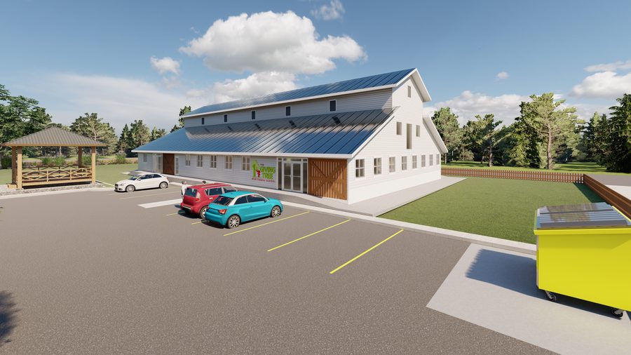Architectural rendering of The Giving Tree Montessori School: a long barn-form building with clapboard siding, a standing-seam roof, clerestory vents and sliding barn doors, showing the school sign and glazed entrance doors along the front.